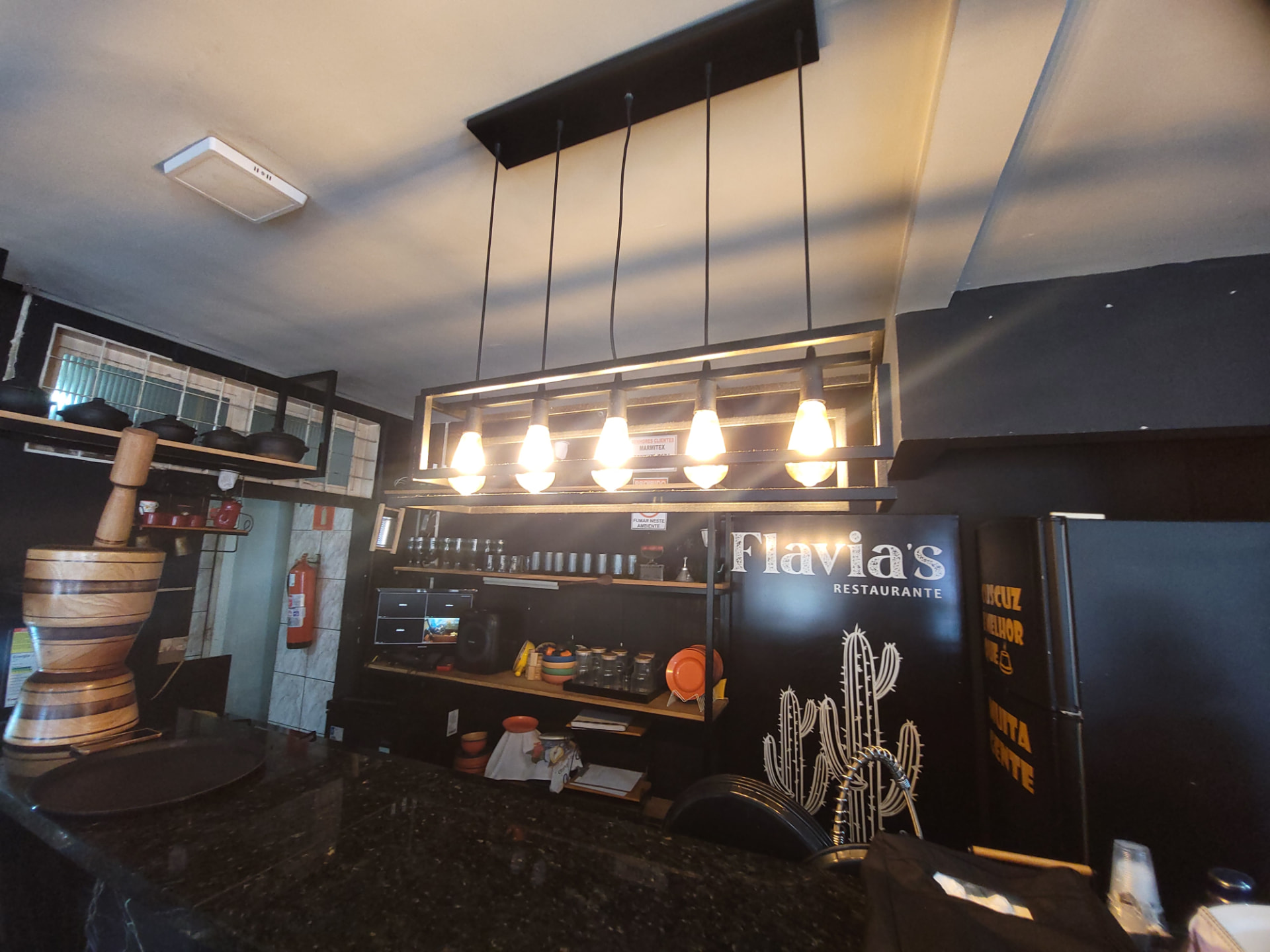 Balcão, luminárias, pilão de madeira e logo do Flavia's Restaurante em Campo Grande