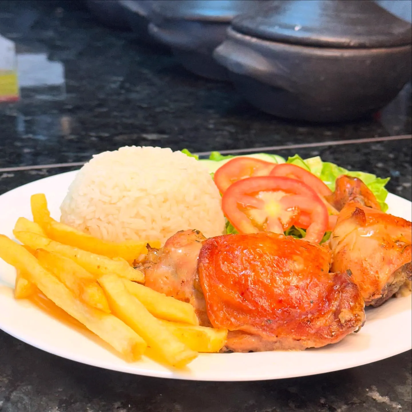 Prato com frango assado, arroz, batata frita e salada servido no Flavia's Restaurante