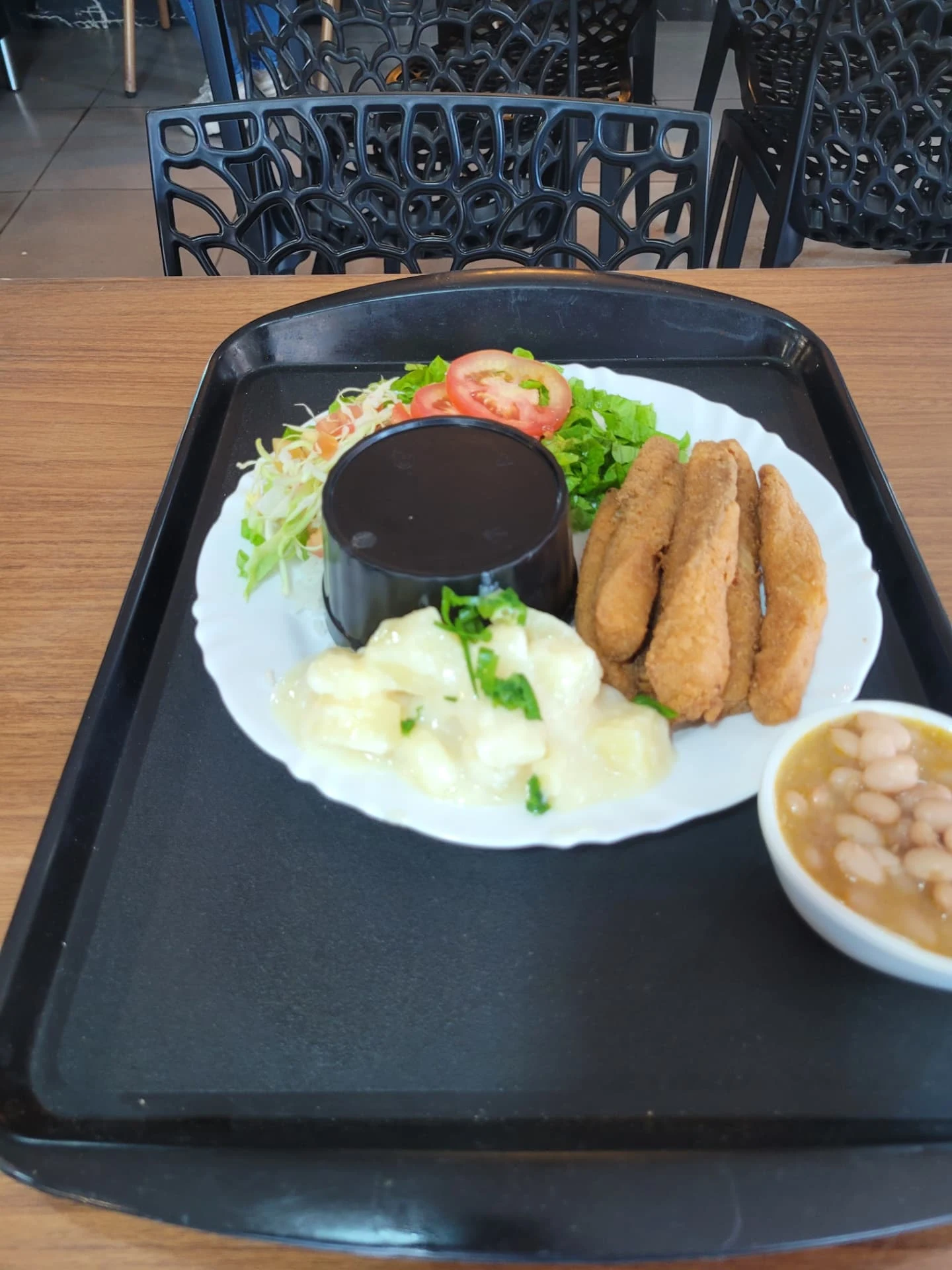 Bandeja com empanados, purê de batata, salada e feijão servida no Flavia's Restaurante